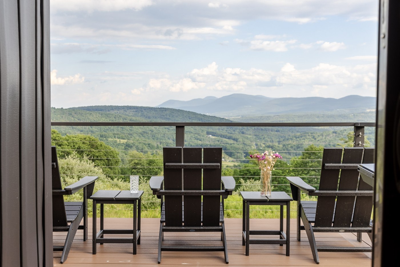 Adirondack chairs on deck with side tables and panoramic mountain views