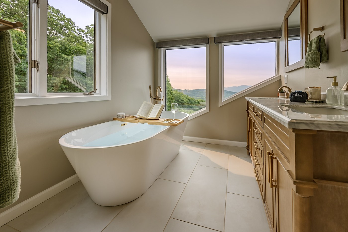 Primary bath soaking tub, vanity, marble counter, and mountain views