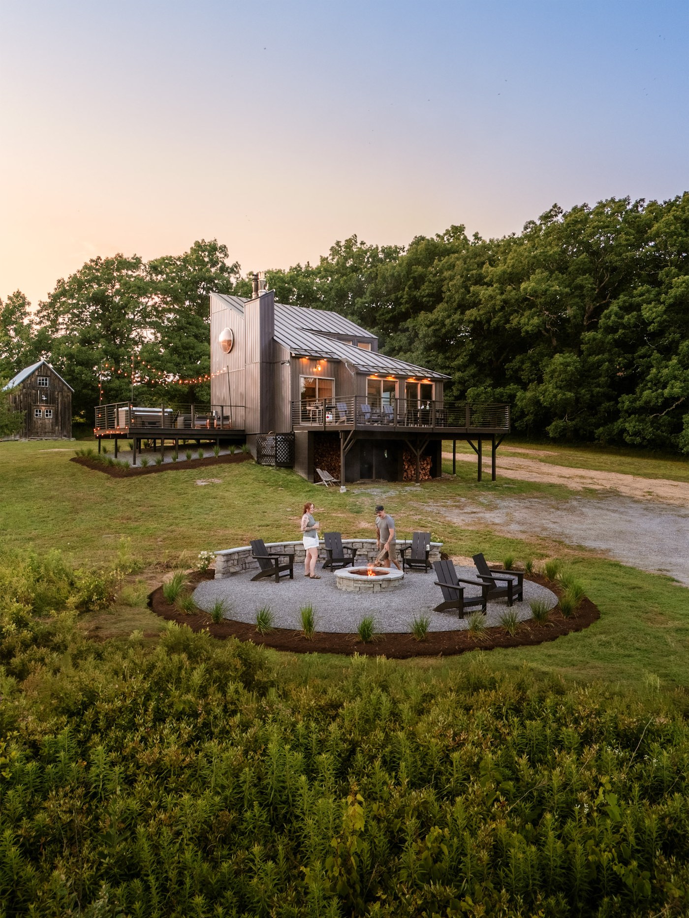 Hollow Sky at dusk — front of the house with guests gathered at the fire pit