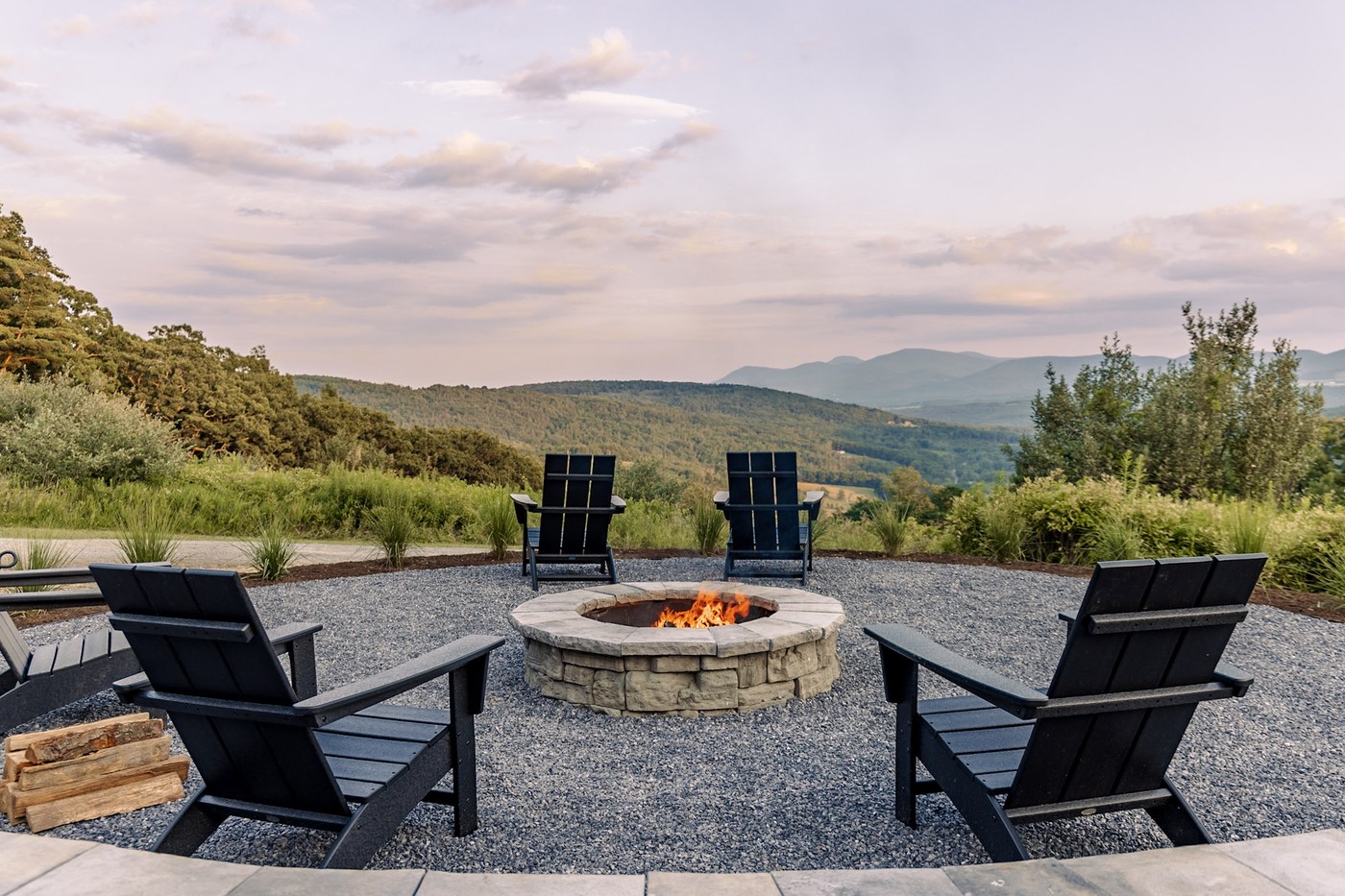 Stone fire pit with four Adirondack chairs and mountain view at golden hour